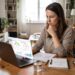 Woman reviewing her credit score and financial documents on a laptop at home.